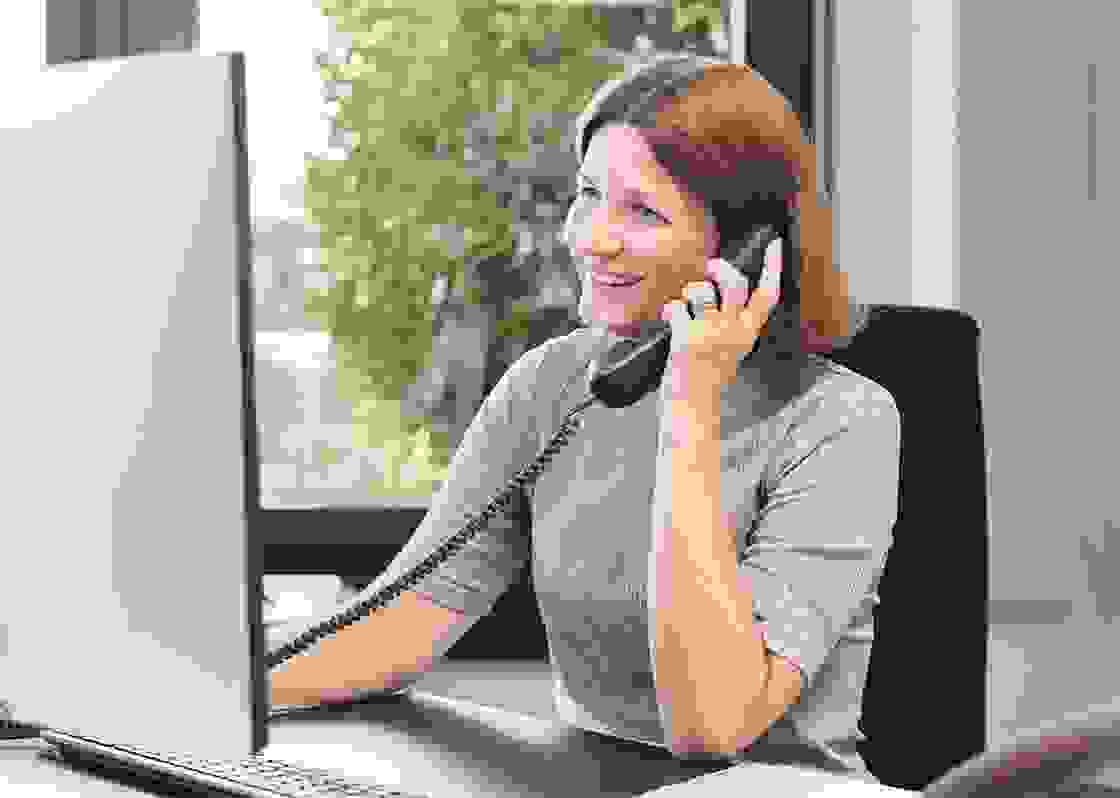 Frau mit hellbraunen Haaren am Telefon