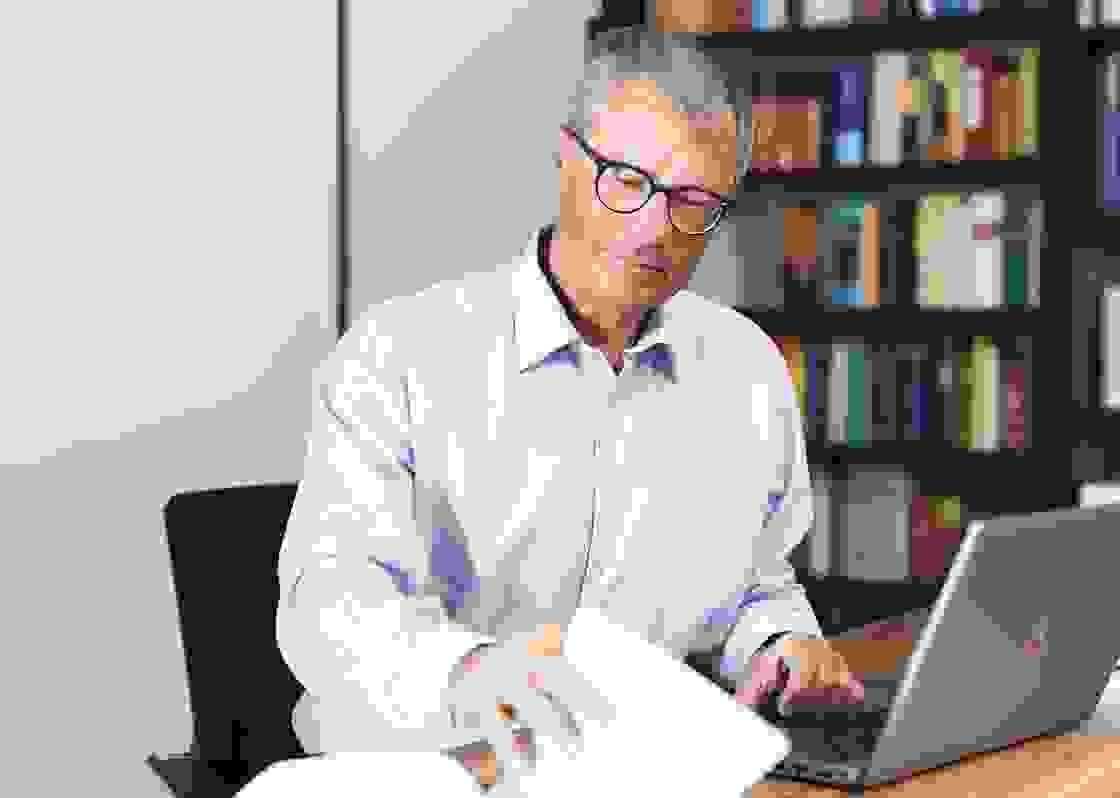 Mann mit hellblauem Hemd und Brille am Arbeitsplatz