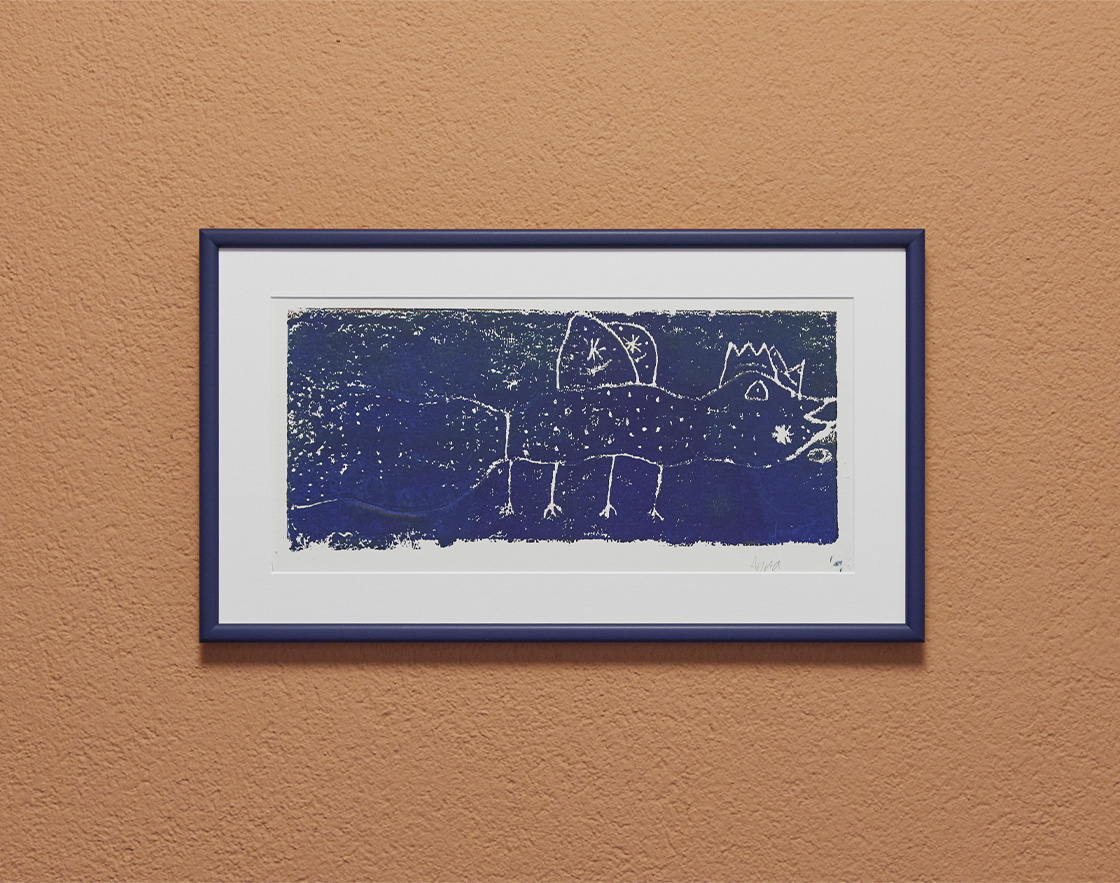 Kunstdruck in schwarzem Rahmen auf hellbrauner Wand.