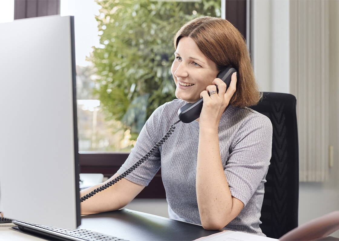Frau mit hellbraunen Haaren am Telefon