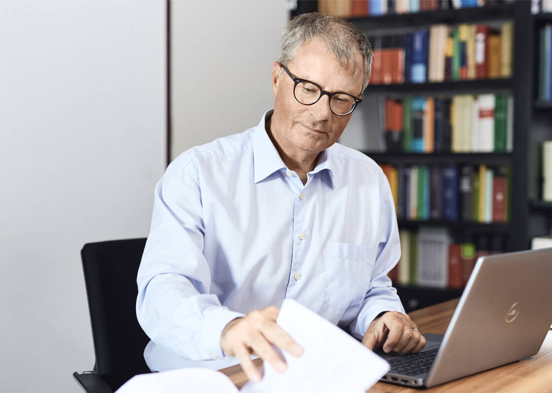 Mann mit hellblauem Hemd und Brille am Arbeitsplatz