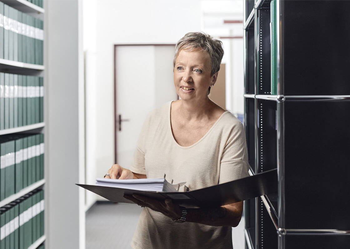 Frau mit Kurzen Haaren die einen Ordner in der Hand hält